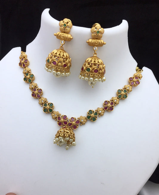 Gold necklace and earrings set with floral designs, featuring green and red gemstones and pearl accents.