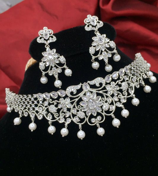 Silver-plated choker set with intricate floral design, adorned with white stones and pearls, accompanied by matching earrings.