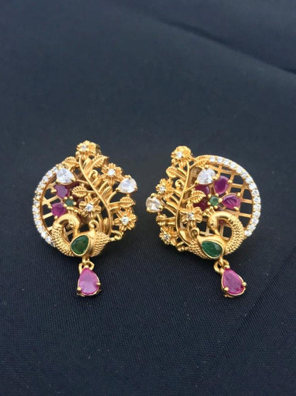 Gold stud earrings with intricate designs, featuring ruby and emerald gemstones, and floral accents.
