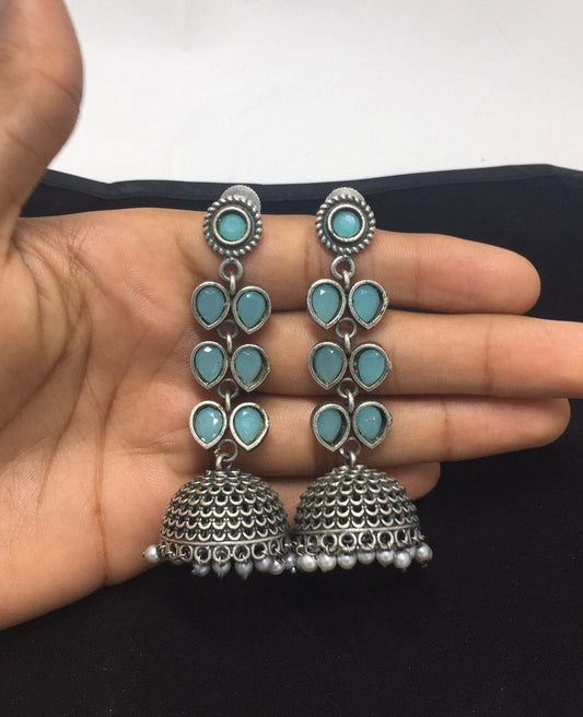 A pair of silver jhumki earrings with mint green teardrop-shaped stones.